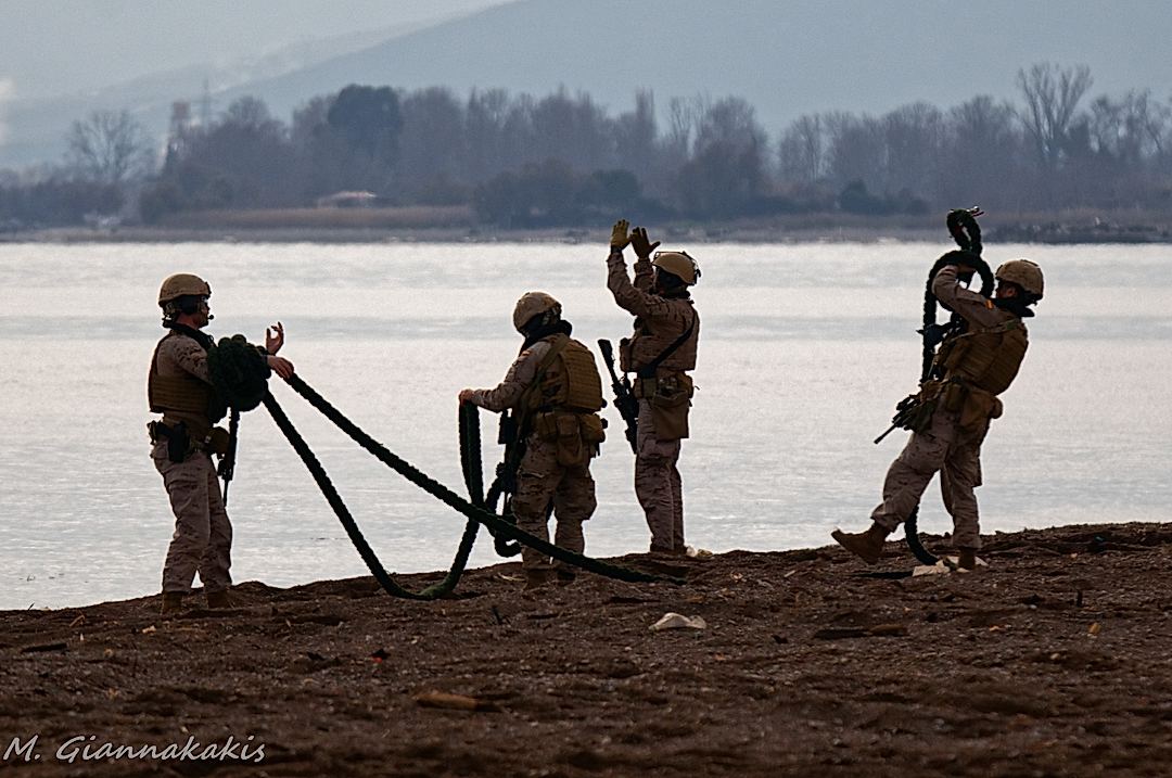 Spanish Marines gathering the ropes used for fastroping from a helicopter, while another one guides the landing craft with the vehicles of the amphibious landing force to the shore
.