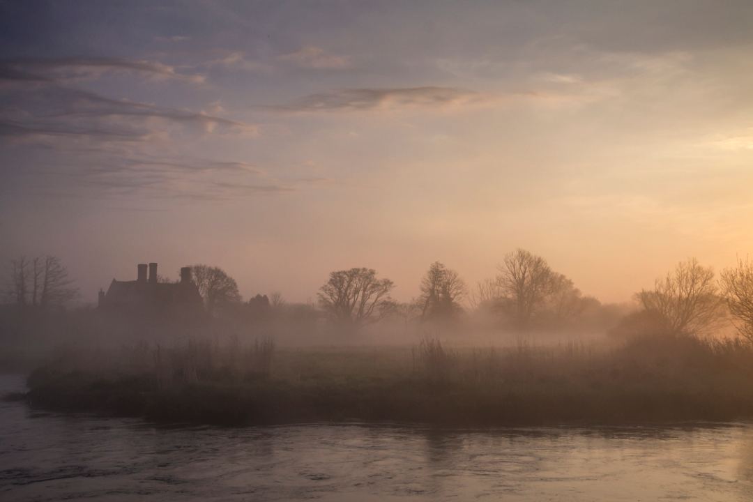 Woolbridge Manor hiding in the mist on the River Frome Dorset UK.