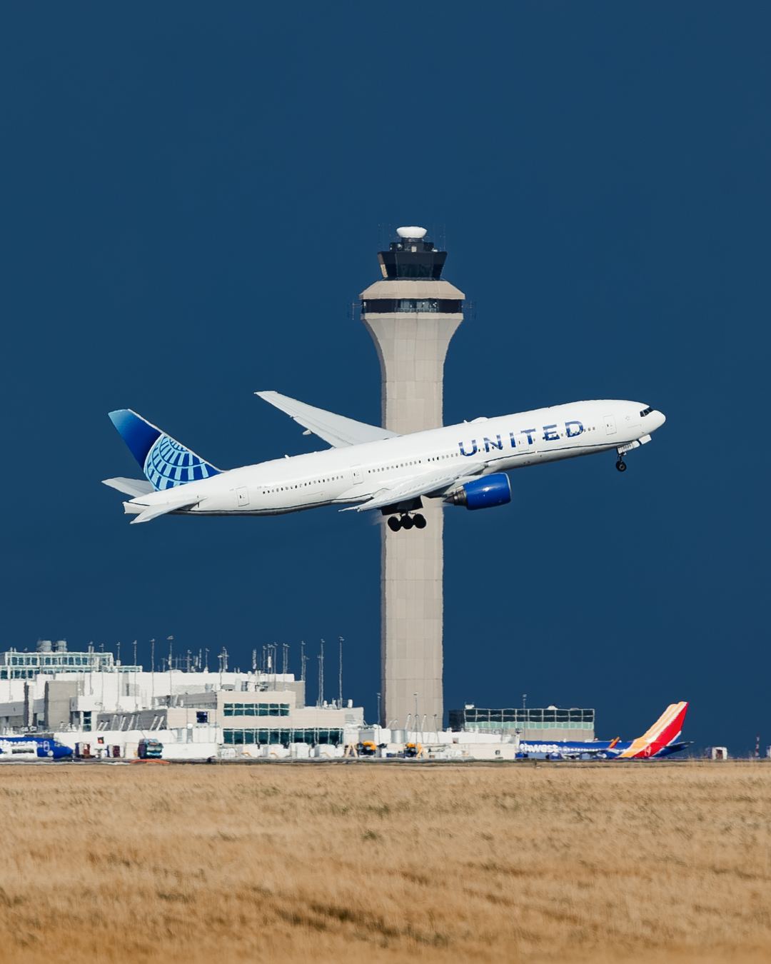 A United 777 turns sharply in front of black skies as it lumbers out for Hawaii