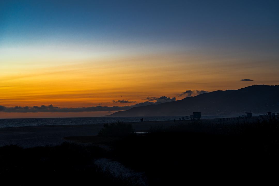 Light mist across the bay at Malibu beach at Sunset, the beach now at rest and the lifeguard watch towers all quiet.