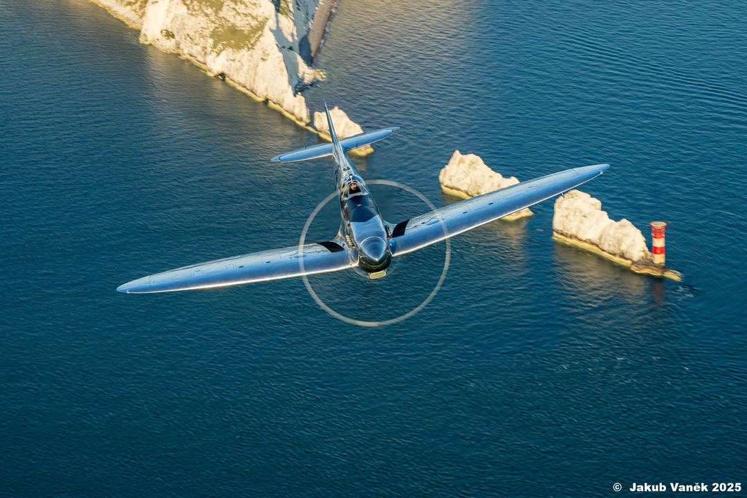 Silver Spitfire flying low over the English coast in the last light of the day.
