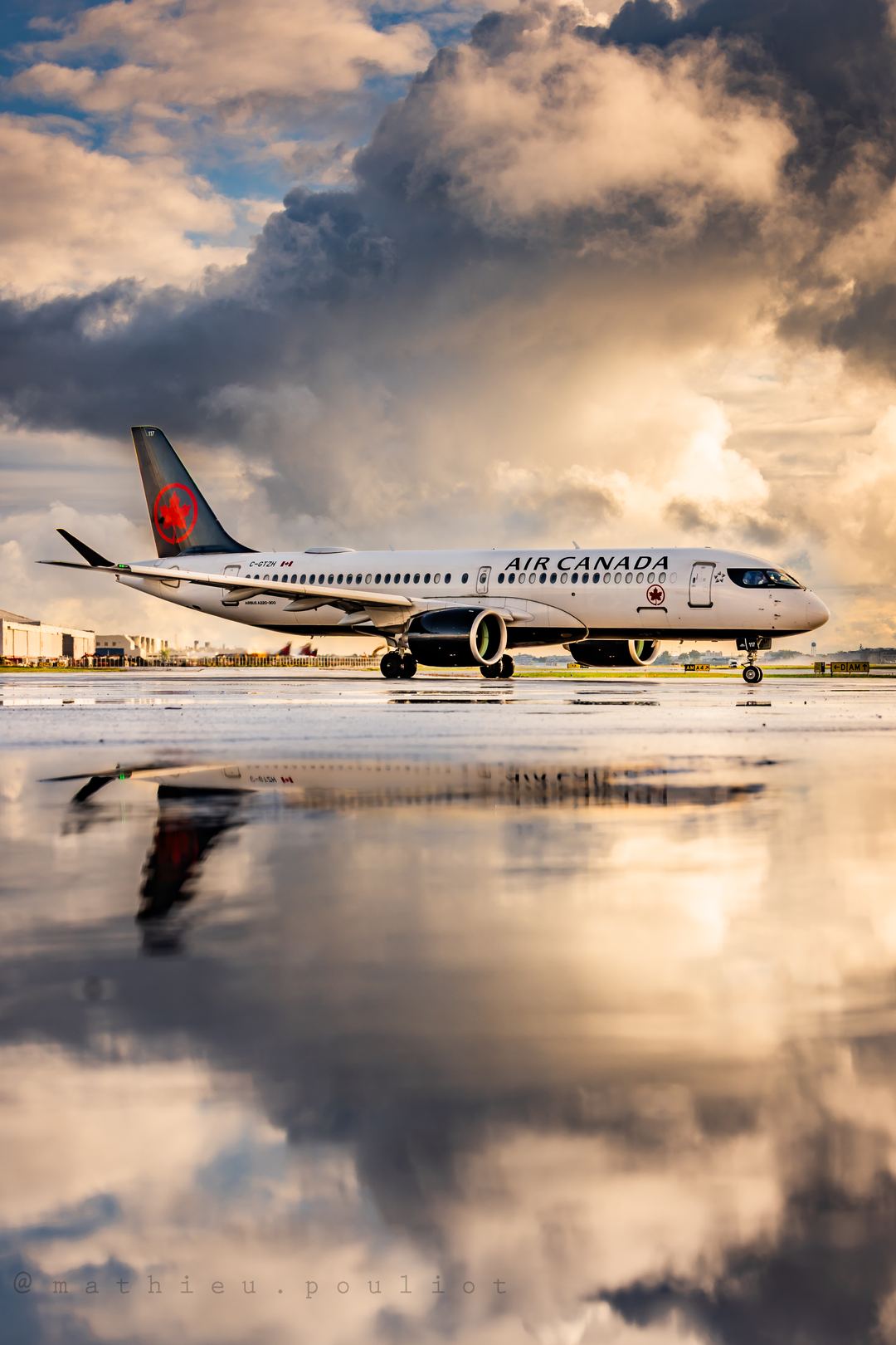 Rising sun lighting up the clouds as this Air Canada A220 taxies for departures.