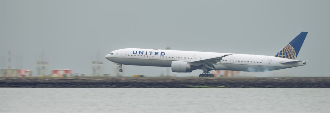 United 77W landing on 28R over the bay and in some light fog 