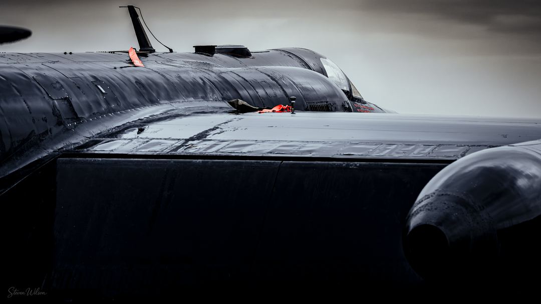 WET, DARK & POISED FOR ACTION

Story, Soaked U2 wings reflecting the bright sky with colour pop on the safety tags. 

Intention: I want them to feel the wet airframe, so I cropped into the wet areas keeping enough airframe to determine aircraft type. 

Attention: Straightened levels, dodge and burn brushes, Linear gradient at top. Radial gradient on canopy area. 

Captivation : I'm hoping audience is led into the frame along the lines of the airframe, drawn to the red colour pop and wet wings. Consideration given to rule of thirds.