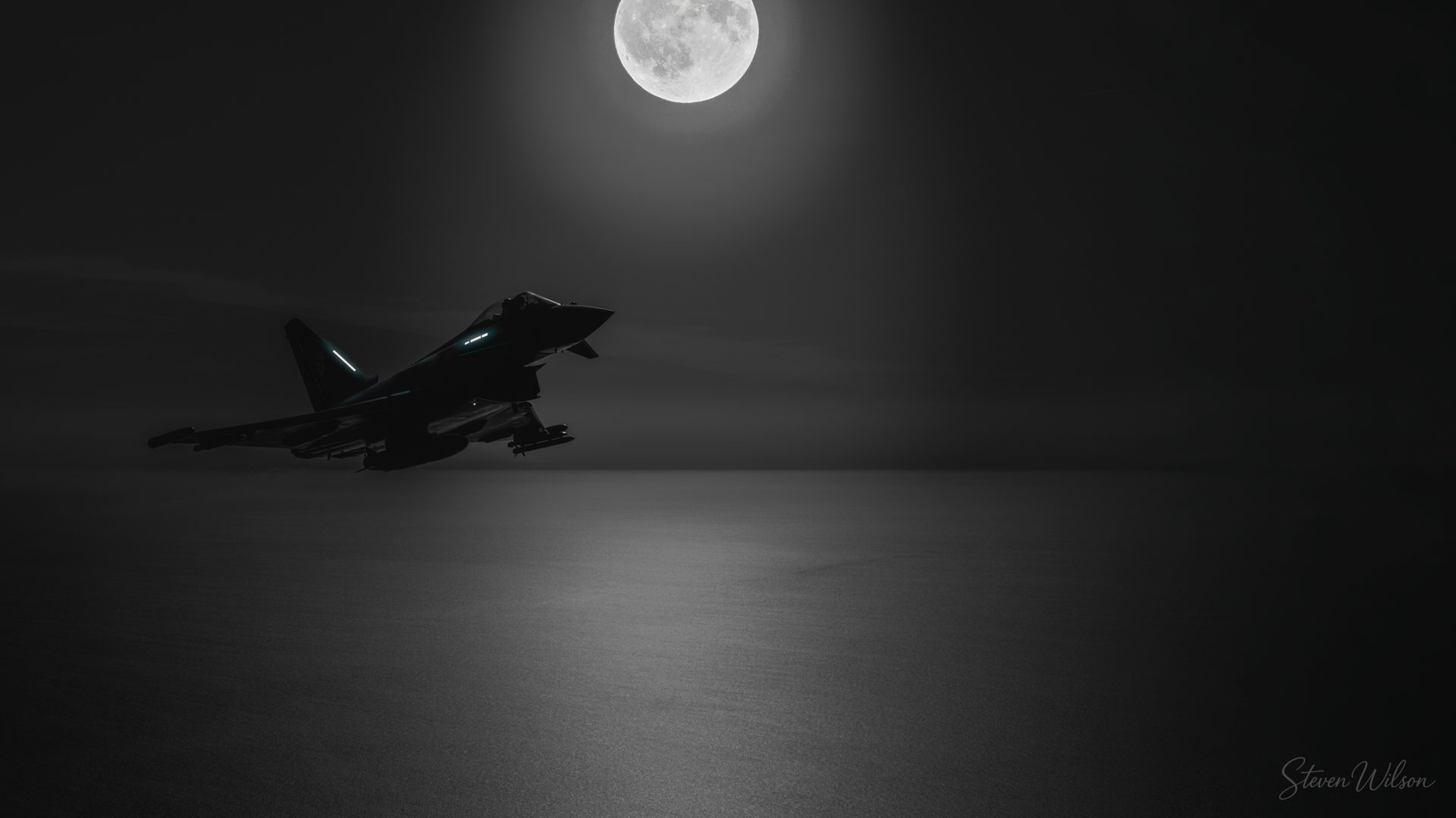 A Typhoon silhouetted in black and white beneath a full moon, with faint blue formation lights on the airframe.