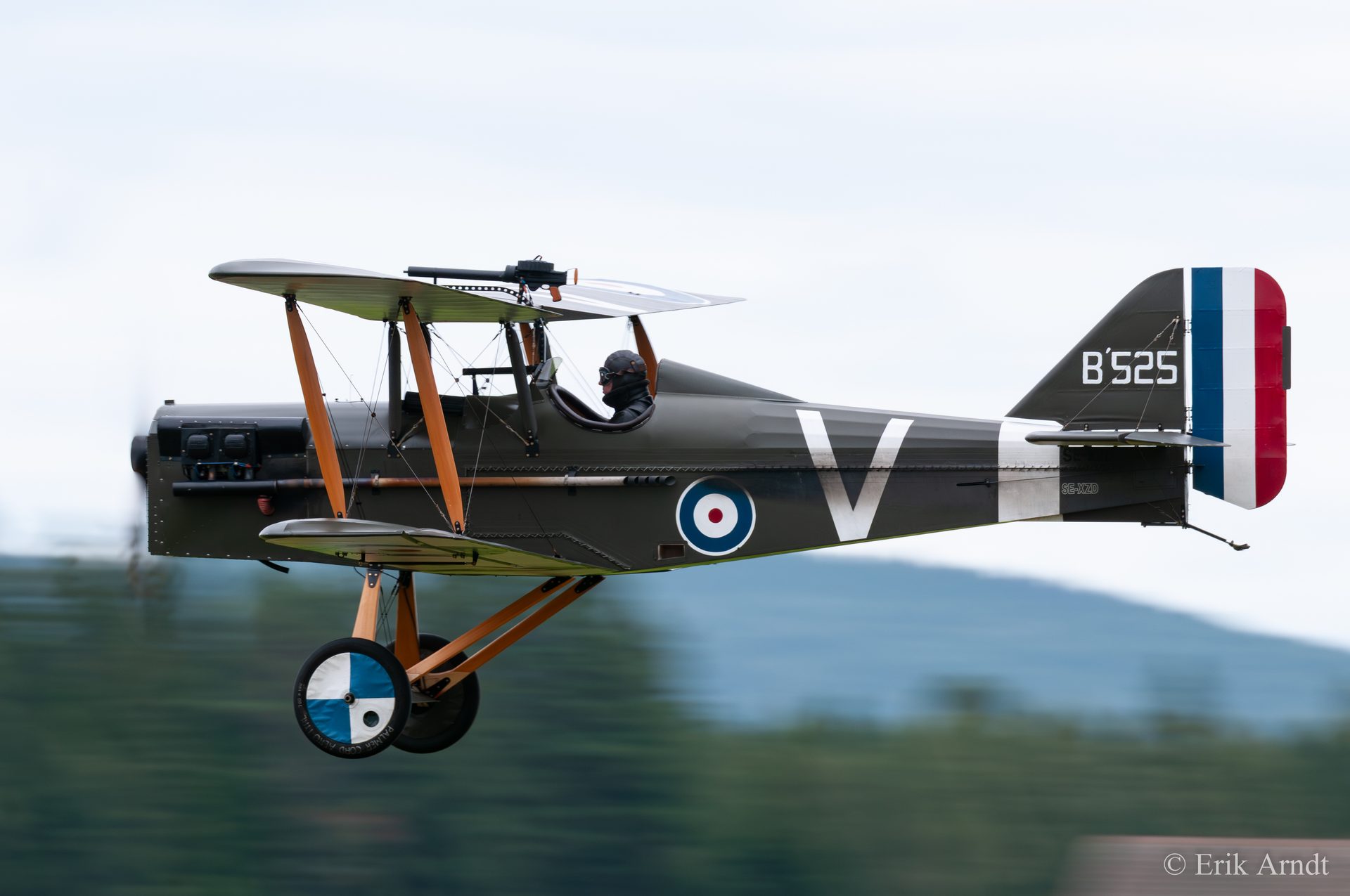 An SE5a biplane in flight, side on, its propeller blurred almost out of sight and the airframe sharp.