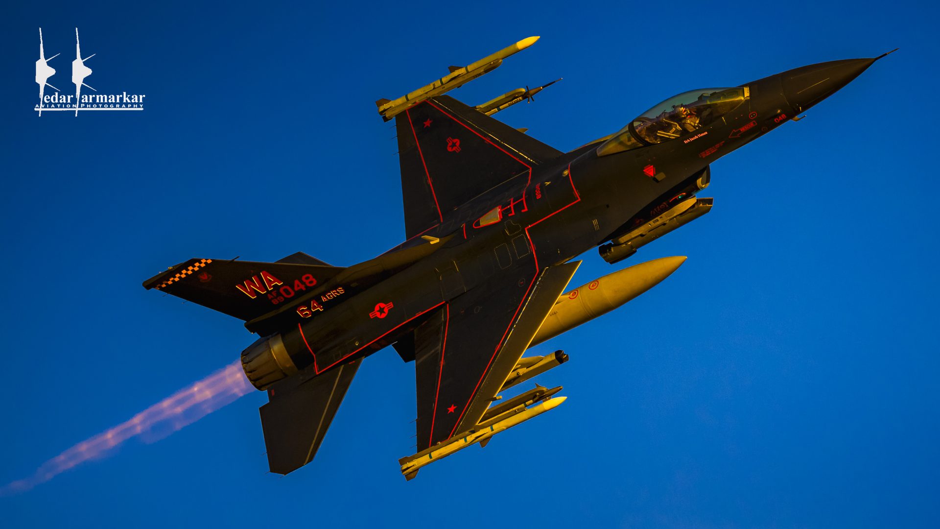An F-16C Viper in an aggressor scheme departing in low golden light